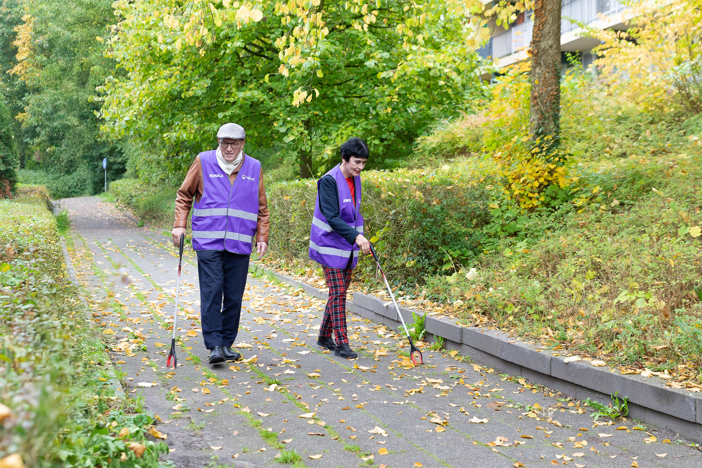 Hier zien we de vrijwilligers Ronald en Jennifer bijdragen aan een schone buurt